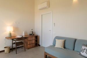 a living room with a blue couch and a desk at Hotel Baia Tartuga in Stintino