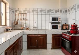 a kitchen with a red stove and microwave at 2 chambres residence Dovv quartier Odja in Yaoundé