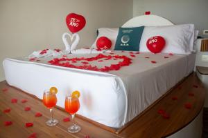 a bed with red roses and two glasses of wine at Primaluna Romantica in La Punta de los Remedios