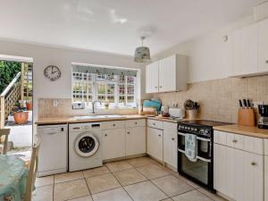 a kitchen with white cabinets and a washer and dryer at 2 Bed in Bridport oc-77557 in Loders +8 photos