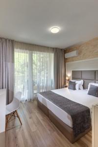 a hotel room with a large bed and a desk at Marina White Sands Beach Hotel-All Inclusive in Obzor +30 photos