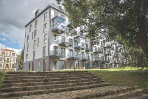 a large white building with stairs in front of it at Apartamentai parke, su vaizdu į upę - Šešupės terasos in Marijampolė