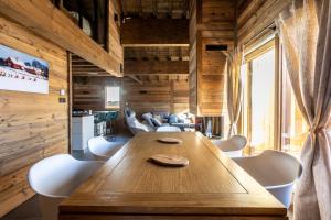 a dining room with a wooden table and white chairs at Chalets Choseaux Lézami in Saint-Sorlin-dʼArves