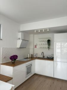 a white kitchen with white cabinets and a sink at Warm Apartment 1 in Bucharest