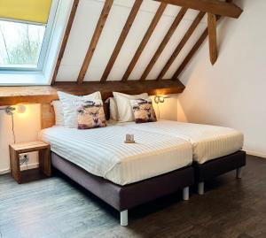 a bedroom with a large bed in a attic at Hoevehotel 'Hof Christina' in Vrouwenpolder