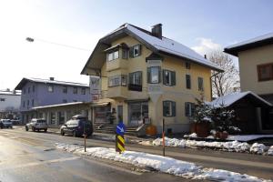 a yellow house on the side of a street with snow at Haus Rieder in Wörgl