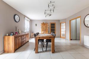 a dining room with a table and chairs and a clock at Maison Ferrer - avec jardin clos in Villeneuve-le-Roi