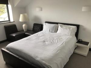 a bedroom with a large white bed and a chair at Gwel Owrek in Tintagel