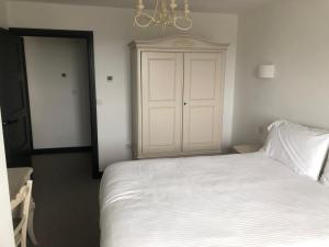 a bedroom with a white bed and a closet at Gwel Owrek in Tintagel