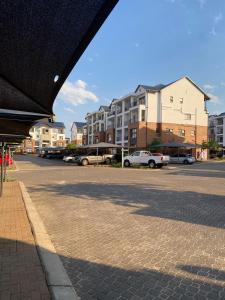 a parking lot with cars parked in front of buildings at The blyde 1 bedroom in Pretoria