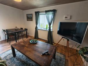 a living room with a table and a large flat screen tv at Cozy guest house with terrace in Aalborg