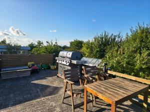 a picnic table and a grill and a wooden table at Cozy guest house with terrace in Aalborg
