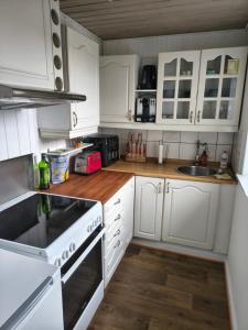 a kitchen with white cabinets and a stove top oven at Cozy guest house with terrace in Aalborg