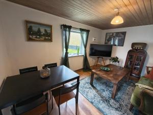 a living room with a table and a tv at Cozy guest house with terrace in Aalborg