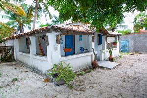 a small white house with a porch and palm trees at Vila Borogodó- Casa in Barra Grande