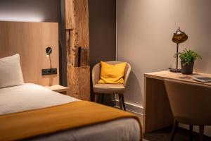 a bedroom with a bed and a desk with a yellow pillow at Hôtel & Restaurant Five Nations in Durbuy