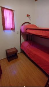 a bedroom with two bunk beds and a wooden floor at Complejo el Cuy in Las Grutas