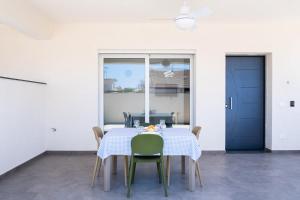 a dining room table with green chairs and a blue door at Residence Casuzze in Marina di Ragusa