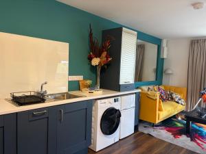 a kitchen with a sink and a washing machine at Hillcrest House Holiday Suites in Donegal