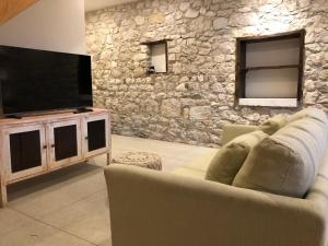 a living room with a couch and a television at La Tranquilitude in Ceyzérieu