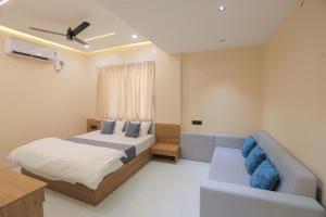 a bedroom with two beds and a blue couch at Srushti Resort in Daulatābād