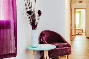 a vase of flowers on a table next to a chair at Apartamentos Madrid in Torrevieja +168 photos