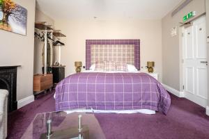 ein Schlafzimmer mit einem lila Bett und einem Kamin in der Unterkunft Cherry Tree in Horbury