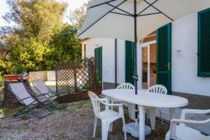 a patio with a white table and chairs and an umbrella at Il Golfo e La Spiaggia - A Due Passi Da Procchio in Marciana