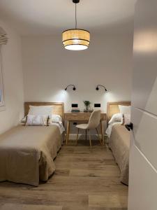 a bedroom with two beds and a desk with a chair at Los Cucos in Cabezuela del Valle