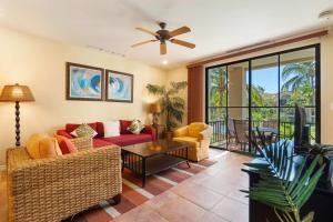 a living room with a red couch and a ceiling fan at Vibrant 3-Bedroom Condo with Resort Amenities, Pools & Beach Club Access in Coco