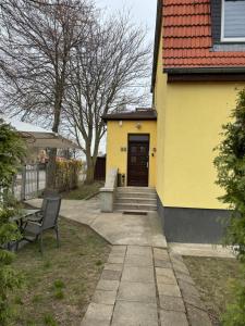 a yellow house with a bench and a door at Hellwig Ferienwohnung 1 in Bernburg