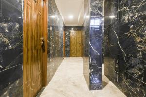 a hallway with black marble walls and a wooden door at Super Hotel O Dabolim Near Goa International Airport in Goa