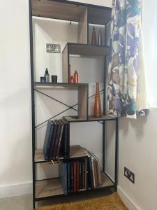 a book shelf filled with books next to a wall at Double Ensuite Ground Floor Easy to Cardiff in Cardiff
