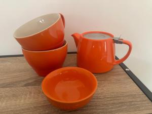 two orange cups and a mug on a wooden table at Double Ensuite Ground Floor Easy to Cardiff in Cardiff