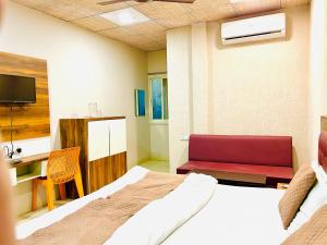 a bedroom with a bed and a desk and a tv at Hotel JT in Indore