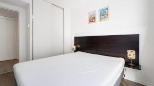 a bedroom with a white bed with a wooden headboard at Virginia N 410 2P4 in Grasse