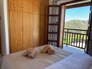 a bedroom with towels on a bed with a balcony at St Visianos stone house in Philousa