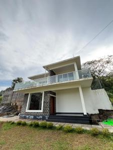 a white house with a balcony on top of it at Horizon house in Vagamon