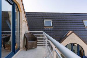 a wicker chair sitting on a balcony next to a building at Casiola - Comfortable Apartment with Scenic Views in De Haan