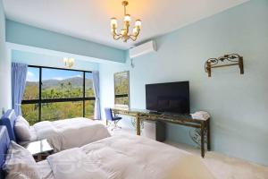 a bedroom with two beds and a desk with a television at Mao Lan Mountain Holiday Villa in Shan-tzu-chiao