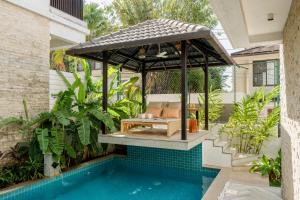a pergola over a swimming pool next to a house at Lindsay Manor AkSh Private Pool 4BHK Lift in Arpora