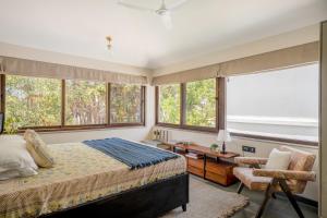 a bedroom with a bed and a chair and windows at Lindsay Manor AkSh Private Pool 4BHK Lift in Arpora +69 photos