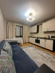 a living room with a couch and a kitchen at Apartment in Almaty
