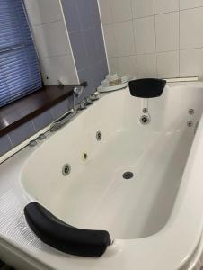 a white bath tub with a black seat in a bathroom at Apartment in Almaty