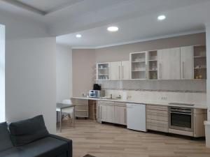 a kitchen with white cabinets and a couch in a room at HOME City Stay Chemnitz in Chemnitz