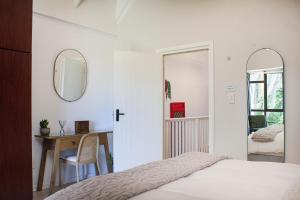 a bedroom with a bed and a table and a mirror at The Milkwood House in Wilderness