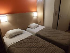 two beds in a hotel room with two pillows at Premiere Classe Agen in Agen