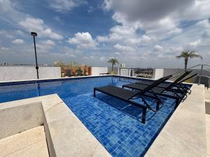a swimming pool with two lounge chairs on top of a building at City Core 2 Bedrooms by AP Smart in Campinas