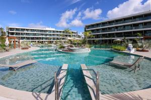 a swimming pool with two chairs and a building at Luxury Flat with Breakfast! in Ipojuca
