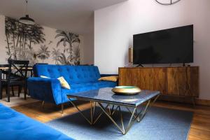 a living room with a blue couch and a tv at AppartUnique - Chez Helder - Standing, Calme & Design in Vichy